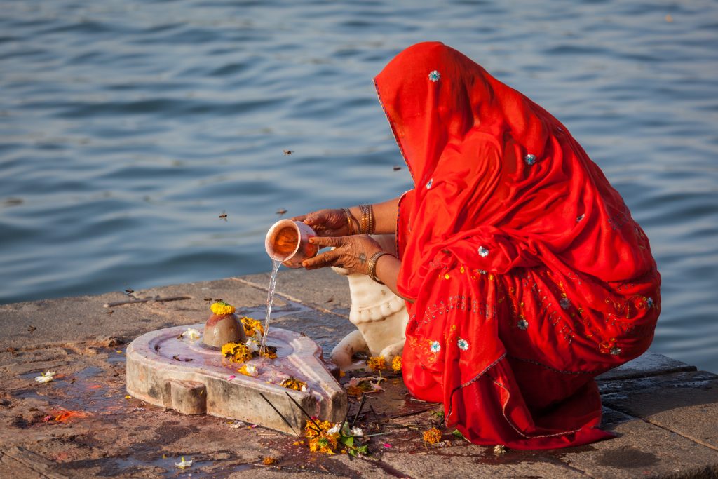 MAHESHWAR, INDIA - APRIL 26: Indian woman performs morning pooja on sacred river Narmada ghats on April 26, 2011 in Maheshwar, Madhya Pradesh, India. To Hindus Narmada is one of 5 holy rivers of India