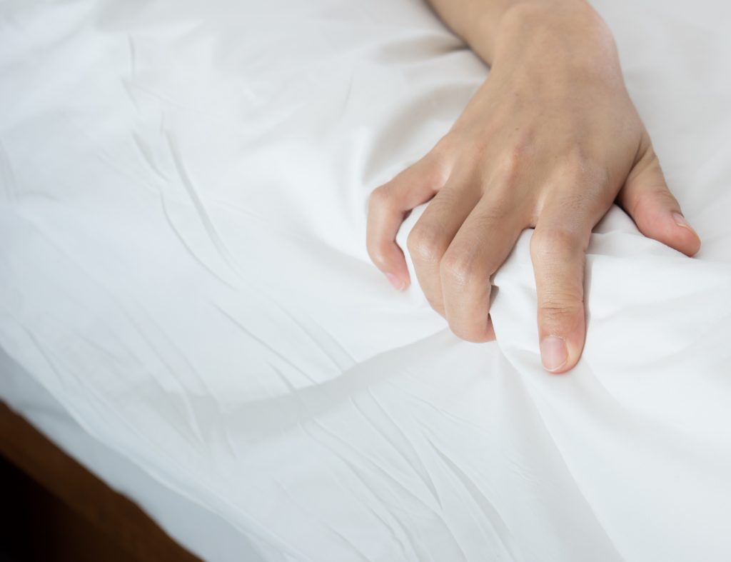 Woman hand grasp bed sheet