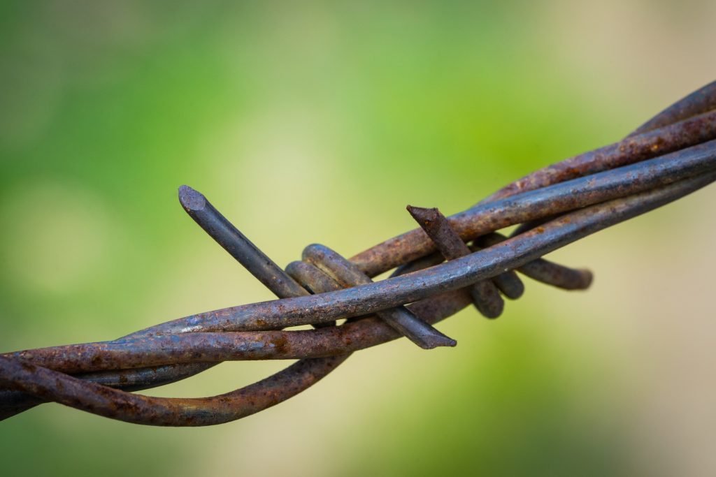 Wrapped metal strands of barbed wire fence.wired tired stress